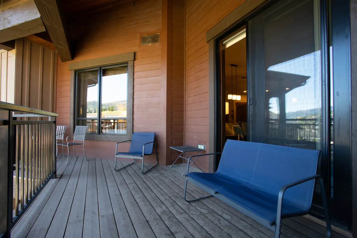 A private balcony with comfortable seating on a wooden deck, offering breathtaking views of mountains under a tranquil sky. The setting is ideal for morning coffee, evening relaxation, or stargazing, embodying a peaceful retreat above it all.