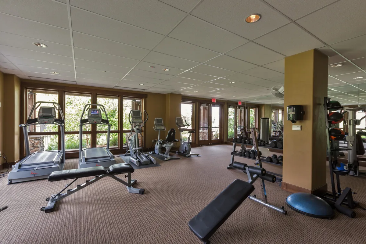 A modern, well-equipped fitness center featuring treadmills, weight machines, and free weights. Large windows provide natural light and views, creating a motivating and energizing workout space for guests of all fitness levels.